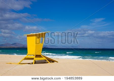 Yellow lifeguard tower. One life guard together with red flag on beach. Point of safe, surviving. Coastal view.