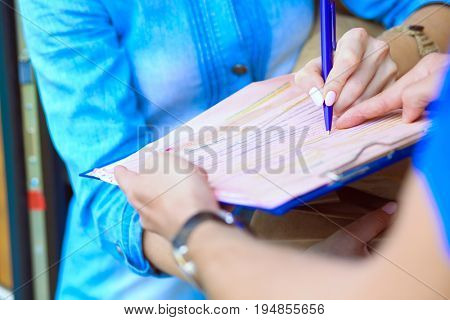 Smiling delivery man in blue uniform delivering parcel box to recipient - courier service concept