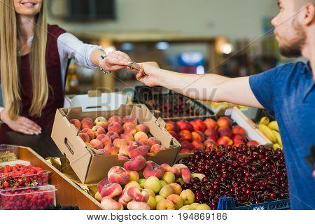 Young man paying cash at food market. Cash payment in close-up. Man pays in cash the seller of vegetables on the market.