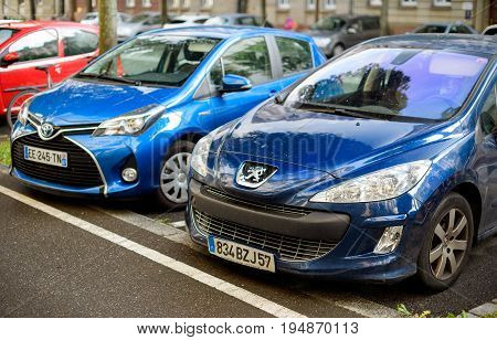 STRASBOURG, FRANCE - MAY 30, 2017: Peugeot 206 and Toyota hybrid car parked on a street near the bicycle lane