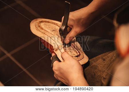 Cropped photo of young man shoemaker at footwear workshop.