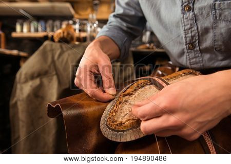 Cropped image of bootmaker sitting in workshop making shoes
