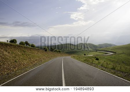 Smooth asphalt road to the mountains road to the distance beyond the horizon to the clouds