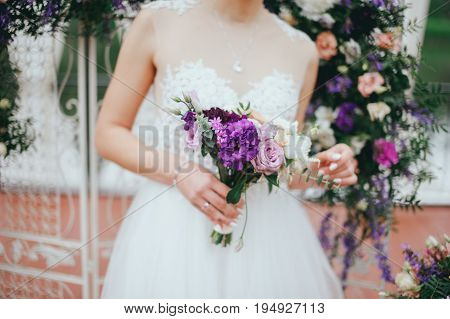 Stylish beautiful bride holds a wedding bouquet in hands