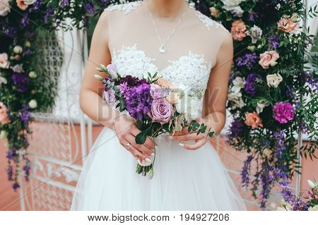 Stylish beautiful bride holds a wedding bouquet in hands