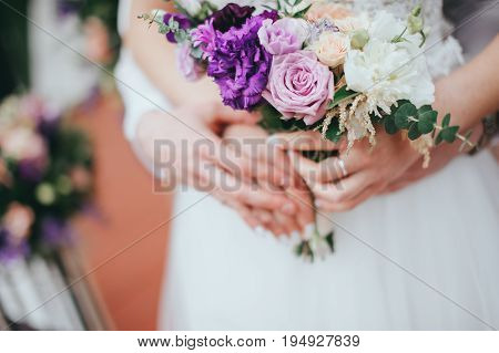 Stylish beautiful bride holds a wedding bouquet in hands