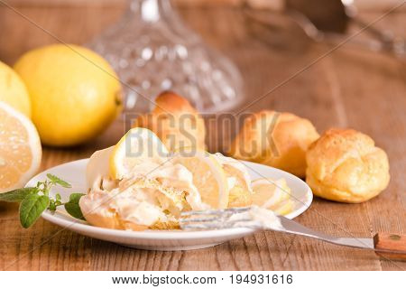 Lemon Profiteroles with custard cream on white dish.