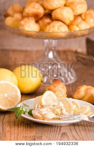 Lemon Profiteroles with custard cream on white dish.