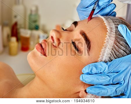 Filler injection for female forehead face. Plastic aesthetic facial surgery in beauty clinic. Beauty woman giving injections. Doctor in medical gloves with syringe beauty injects .