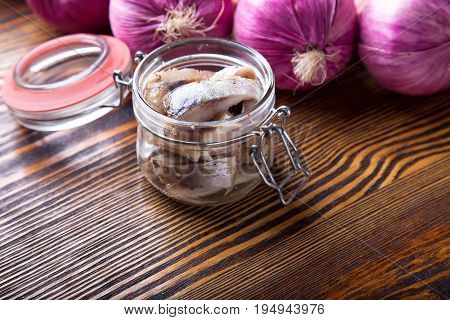 Marinated herring in a jar  on a wooden table
