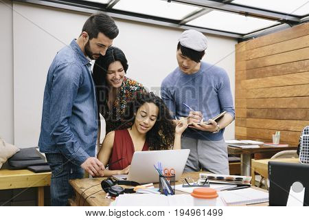 Startup of four multiethnic people discussing joyfully ideas in a modern coworking espace