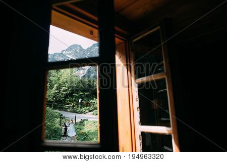 a view through a window facing the bride and groom with mountain views