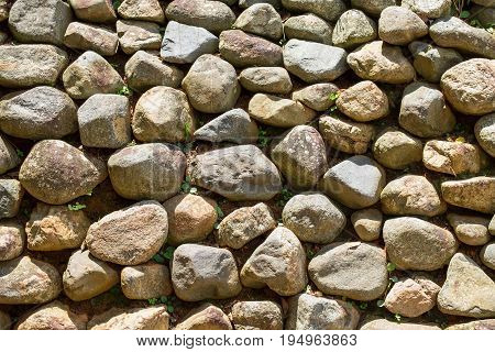 Slope and earth retaining wall made of stone and rocks. Earth material wall abstract texture background