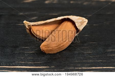 Uzbek open inshell almonds on wooden background, closeup