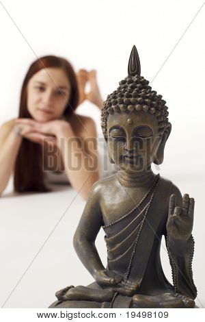 Statua di Buddha con giovane donna sdraiata in abiti bianchi su sfondo bianco, chiave di alta immagine.