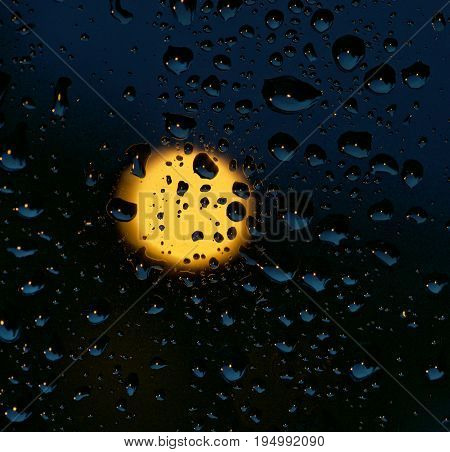 Water and rain drops on the glass and full moon in the background, abstract view, Drops of rain on blue glass background / drops on glass after rain