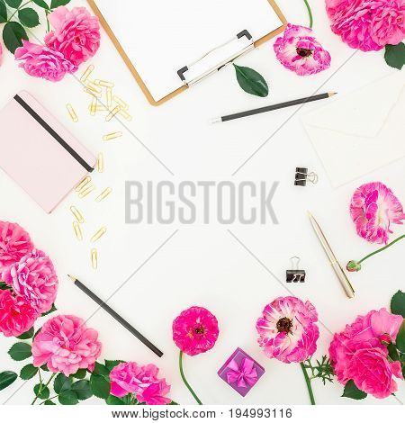 Pink feminine workspace with clipboard, notebook, purple roses and accessories on white background. Flat lay, top view. Blogger of freelancer workspace