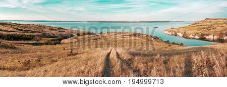 Scenic sea view from top of hills. Beautiful summer background. Amazing landscape with yellow meadows green trees blue sky steep cliffs and picturesque bay. Panoramic photo. Camping rest relax.