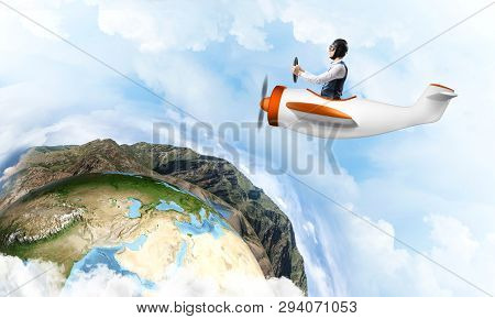 Happy Pilot Driving Small Propeller Plane On Background Of Blue Sky With Clouds. Traveling Around Th