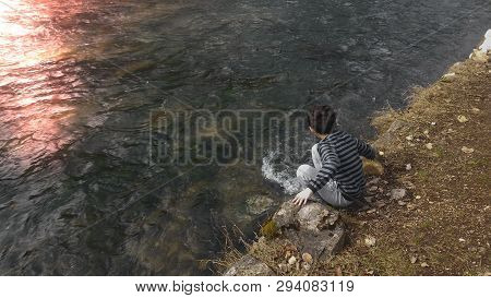 Young Boy Enjoying The Picturesque View Of The River.