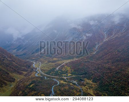 Drone Photo Of Several Small Waterfalls In Mountains With Clouds Covering Them Near Bøjabreen Glacie