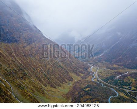 Drone Photo Of Several Small Waterfalls In Mountains With Clouds Covering Them Near Bøjabreen Glacie
