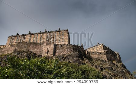 A Dramatic View Of A Sunlit Edinburgh Castle With Heavy Clouds Above
