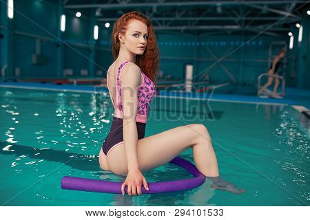 A Beautiful Young Red-haired Girl In A Fashionable Swimsuit In The Style Of The 80s Stands With A No