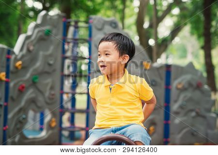 Happy Asian Kid Playing Seesaw Playground. Cute Boy Child Excercise On Equipment To Playful And Joyf