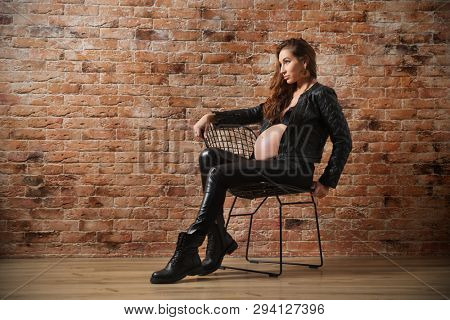Pregnant woman in leather clothes on brick wall background (normal ver)