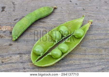 Uncapped Pod Of Fresh Green Peas On Wooden Table Close-up