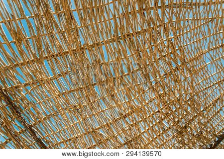 Lonely Wicker Sun Umbrella At Mediterranean Beach By Sea. Natural Bamboo Sunshades And Summer Umbrel