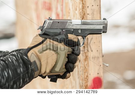 Close-up Detail View Of Hands In Gloves Holding Gun