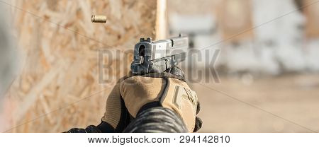 Close-up Detail View Of Hands In Gloves Holding Gun