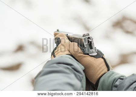 Close-up Detail View Of Hands In Gloves Holding Gun