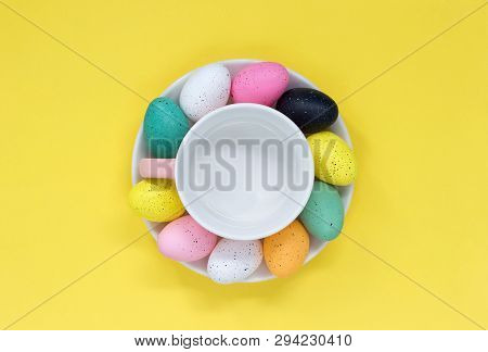 Colourful Easter Eggs Placed Around A Tea Cup, On A Yellow Background