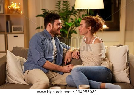 leisure and people concept - happy couple talking at home in evening