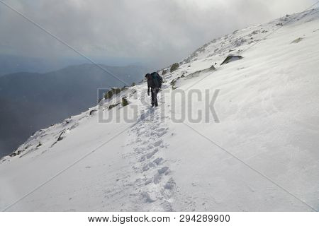 Climbing a snowy mountain with huge backpack