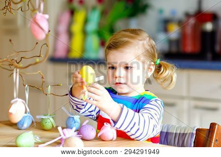 Cute Little Toddler Girl Decorating Tree Bough With Colored Pastel Plastic Eggs. Happy Baby Child Ha