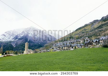 Picturesque Town In A Vall De Boí,  Catalan Pyrenees, Spain. Romanesque Church And Snow Mountains On