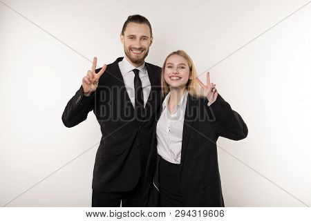 Two Employees Laugh Happily At The End Of The Working Week, Showing Viktory Sign And Looking At The 
