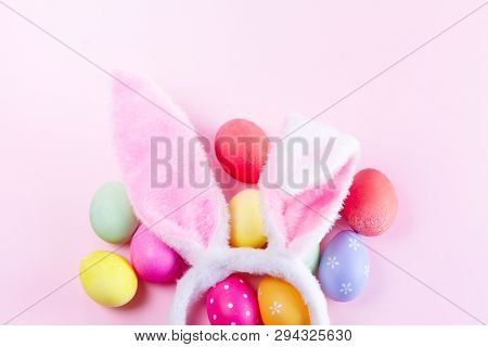 Easter Rabbit Flaffy Decarative Ears And Colored Easter Colored Eggs On Pink Background, Flat Lay