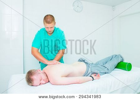 Patient Receiving Massage From Therapist. A Chiropractor Does Deep Tissue Massage On Man's Shoulder 