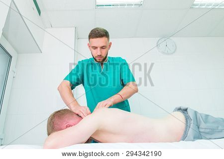 Patient Receiving Massage From Therapist. A Chiropractor Does Deep Tissue Massage On Man's Shoulder 