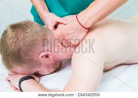 Physiotherapist Massaging Male Patient With Injured Neck Muscle. Sports Injury Treatment, Reabilitat
