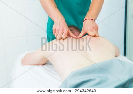 Patient Receiving Massage From Therapist. A Chiropractor Does Deep Tissue Massage On Man's Shoulder 
