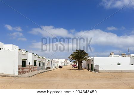 Empty Street With Sand And White Houses And A Palm Tree In Caleta De Sebo On The Island La Graciosa 