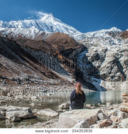 Young Woman Watching Beautiful View Of Manaslu Mountain Range, Birendra Lake.  Lady Sits In Front Of