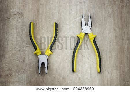 Two Yellow Combination Plier On Workshop Wooden Table.
