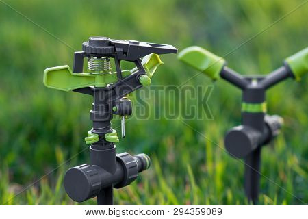 Two Water Sprinklers. Blurred Green Background. Selective Focus. Watering Concept.